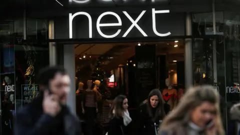 Reuters Four people walk out of a Next store 