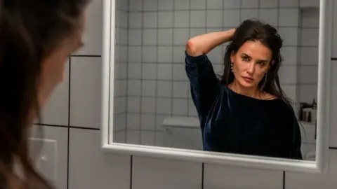 Mubi Demi Moore looking in the mirror in The Substance