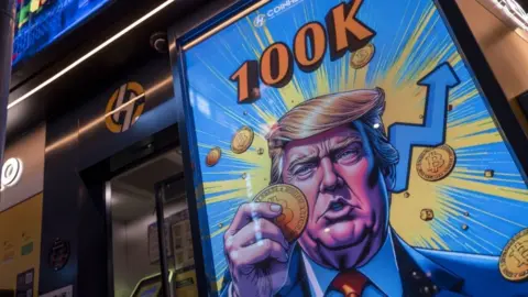 Getty Images A cartoon image of Donald Trump holding a bitcoin displayed at a Coinhero store in Hong Kong.