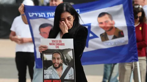 EPA Einav Zangauker, the mother of Israeli hostage Matan Zangauker, holds a poster of her son reading 