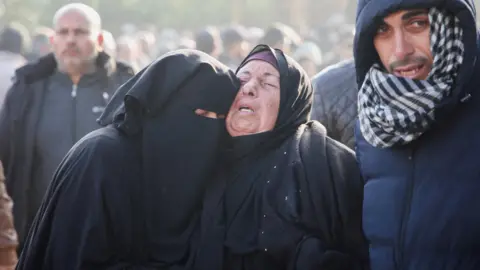 Reuters Two grieving women embrace near the bodies of Palestinians killed in Israeli air strikes, outside Nasser hospital, in Khan Younis, southern Gaza. Two men are seen either side of them and more people are in the background