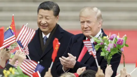 Getty Images US President Donald Trump, right, and Xi Jinping, China's president, greet attendees waving American and Chinese national flags during a welcome ceremony outside the Great Hall of the People in Beijing, China, on Thursday, 9 November, 2017