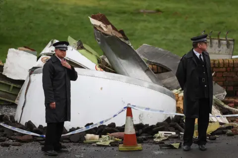 Getty Images Actors playing police officers stand in front of wreckage of the plane while filming the Sky TV drama in Bathgate, West Lothian