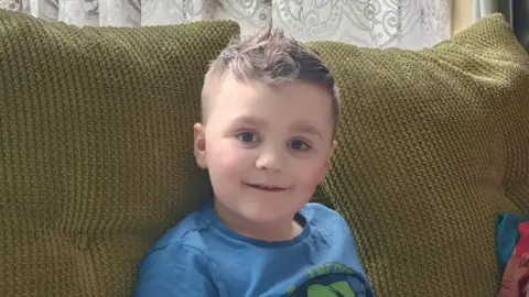 Rachel Morgan Seven-year-old Max sitting on a sofa and smiling at the camera.