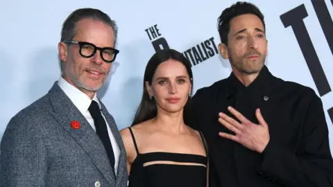 Getty Images Guy Pearce, Felicity Jones and Adrien Brody pose on the red carpet at The Brutalist Los Angeles premiere in December.