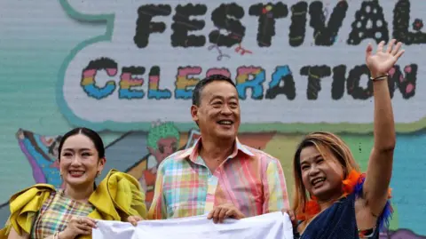 Getty Images Thailand's Prime Minister Paetongtarn Shinawatra (L) and former PM Srettha Thavisin (centre) are smiling alongisde an activist at the Bangkok Pride Festival last year. 