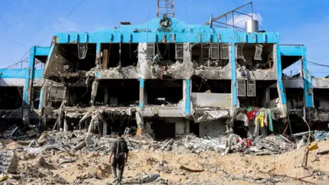 Getty Images A man walks past the destroyed UN Palestinian refugee agency in Jabalia