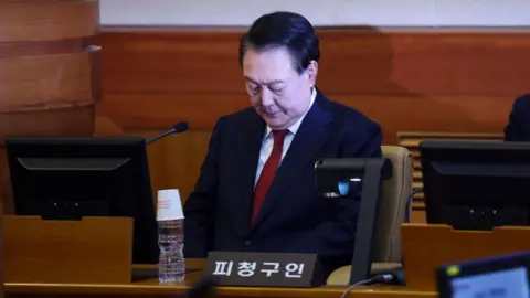 EPA South Korean Yoon Suk Yeol looking downwards while sitting in the dock in a courtroom