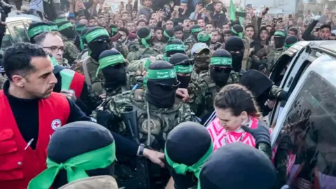 Getty Images One of the three Israeli hostages released on Sunday in Gaza is handed over by Hamas fighters to a member of the Red Cross.