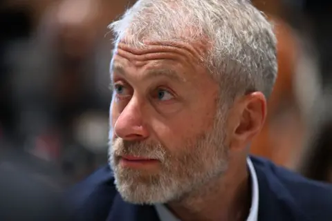 Getty Images A close of up a bearded Roman Abramovich in a blue suit and white shirt looking to his right