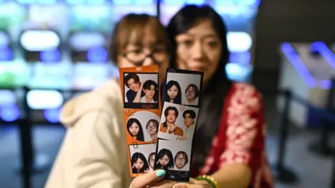 Getty Images This photo taken on April 23, 2024 shows Thai fans hold photographs of popular 