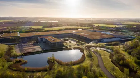 Rolls-Royce Motor Cars An aerial view of Rolls-Royce's Goodwood site in West Sussex with a sunburst and reflection on its lake