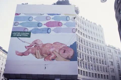 Getty Images A newborn baby is depicted on a billboard crying, next to colourful condoms.