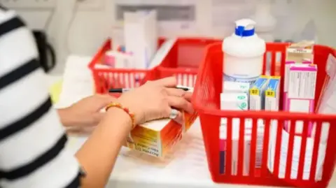 Getty Images Image shows a pharmacy counter with baskets of prescriptions and medications 