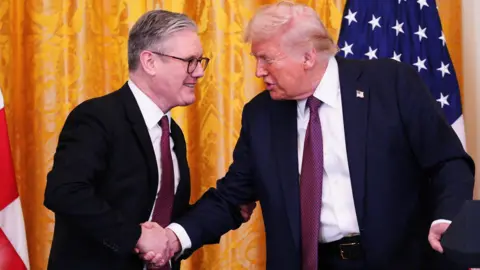 Reuters Sir Keir Starmer and Donald Trump shake hands in front of a yellow curtain and US flag ahead of their news conference