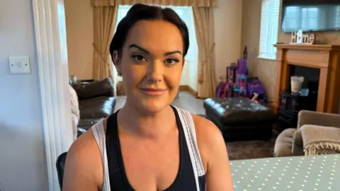 BBC A woman wearing sports clothes with brown hair tied up looking directly at the camera 