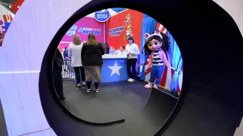 Getty Images A display at the toy fair with people clustered around the booth from the back and a giant doll with cat ears