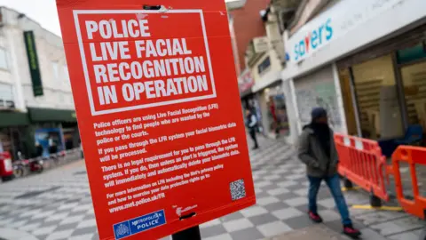 Jordan Pettitt/PA Wire A red sign fixed to a lamppost explaining the Metropolitan Police was deploying the use of live facial recognition technology in Croydon, south London, on Friday February 9, 2024. A QR code is on the bottom right corner of the sign which members of the public could scan for more information. The bottom left corner of the sign features the Metropolitan Police insignia.