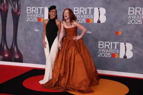 Getty Images Alex Scott in a black and white outfit and Jess Glynne in a burnt orange dress