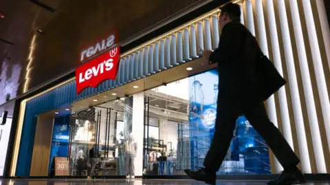 Getty Images Silhouette of a man walking past a shop selling Levi's jeans