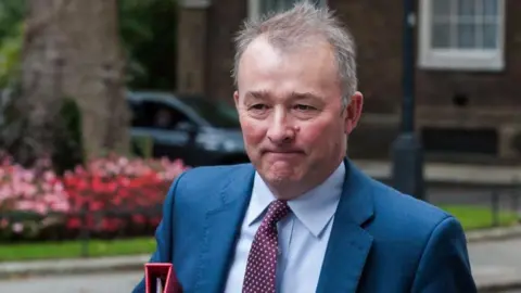 Getty Images Simon Hart walking up Downing Street with a tight-lipped expression and carrying a red file under his arm.