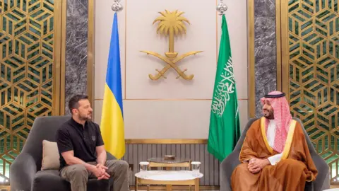 Reuters Ukranian President Volodymyr Zelensky and Saudi Crown Prince Mohammed Bin Salman sit on chairs across from one another 