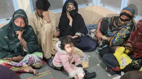 Getty Images A group of passengers, among them women and a little girl, wait at the Mach railway station in Pakistan after being released from a hijacked train