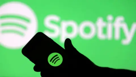 Reuters A smartphone is seen in front of a screen projection of Spotify logo