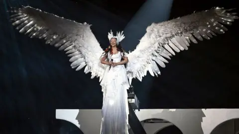 Getty Images Jade Thirlwall in a white gown and giant angel wings