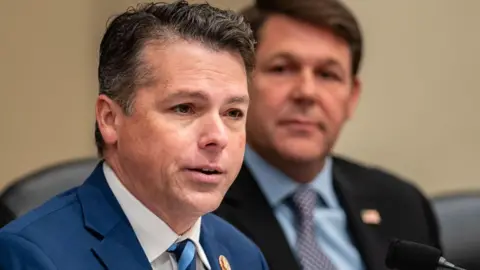 Getty Images Headshot of Brendan Boyle wearing a suit and tie. Another man is sitting behind him out of focus.