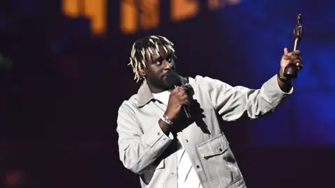 Getty Images Myles Smith holds aloft a Brit Award trophy