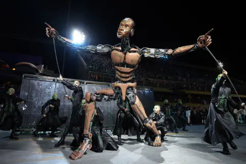 Getty Images A robot puppet and performers dressed in black from the Mocidade Independente de Padre Miguel school