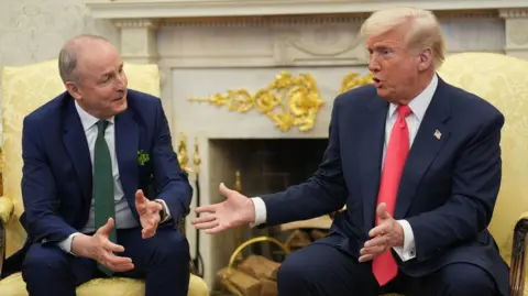 PA Media Micheál Martin sits in the Oval Office in a chair opposite Donald Trump. Martin is speaking and has his arms open. Trump is sat with his hands held and is looking at Martin.