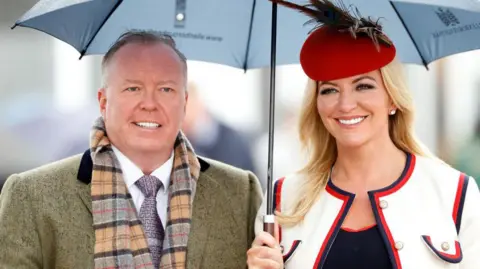 Getty Images Michelle Mone pictured standing under an umberella next to her husband, Doug Barrowman, attending the Cheltenham Festival in 2019