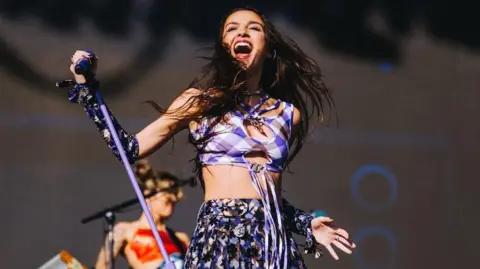 Olivia Rodrigo poses with her microphone stand, while playing at the Glastonbury Festival in 2022