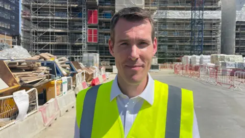 Matthew Pennycook stands on a building site in high-vis vest 