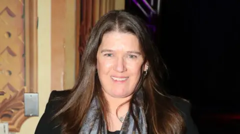 Getty Images Mary Trump smiles at the camera. She wear a grey scarf and black blazer. 