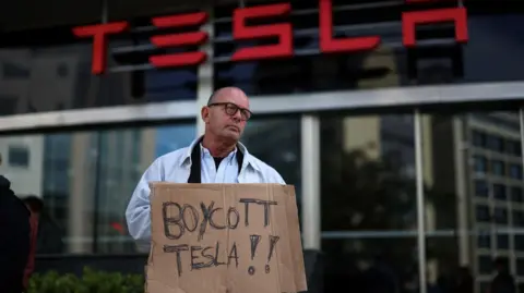 Reuters A man holds a sign - made from what looks like a scrap piece of cardboard - which reads 