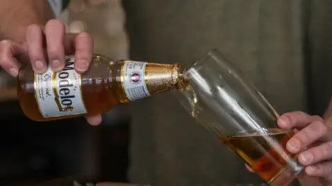 Getty Images A barman pours a bottle of Modelo beer into a glass 