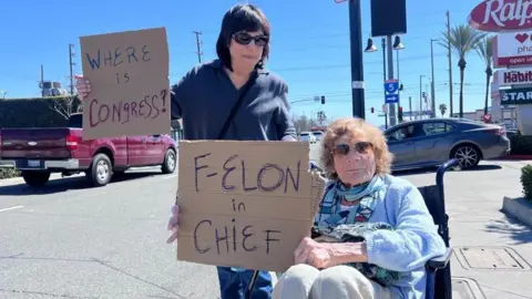 BBC One woman stands and holds sign that reads 