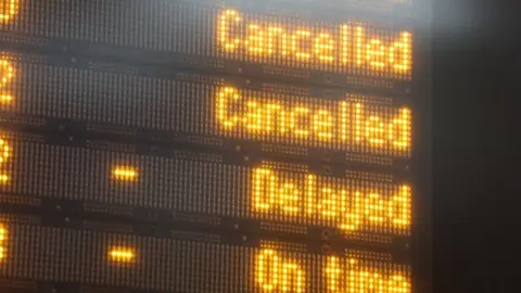 PA Close up image of a display board in a train station. The board says cancelled, cancelled, delayed and on time.